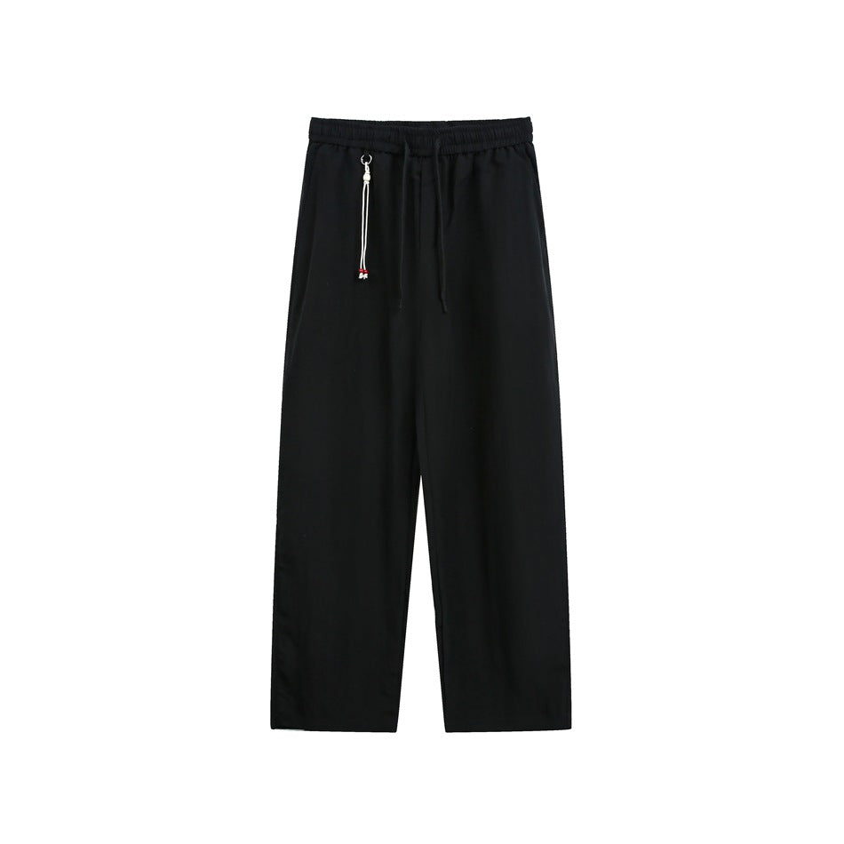 Black straight-leg drawstring pants with elastic waistband and white beaded cord charm, front view