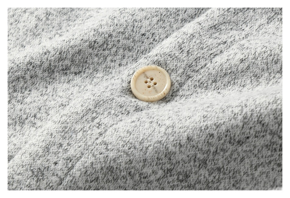 Detail of a cream four-hole button against textured light gray marled knit.
