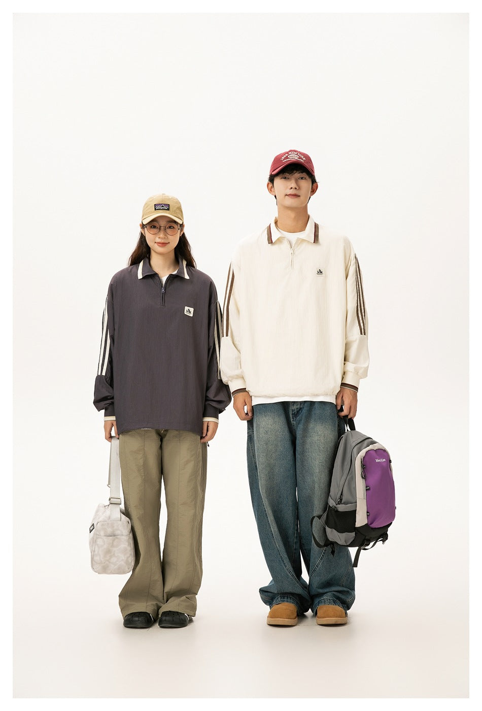 Two models wear oversized quarter-zip pullovers: charcoal with cream sleeve stripes and cream with brown stripes.