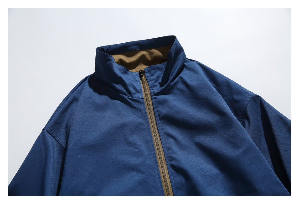 Close-up of the navy jacket's stand collar and upper front, showing the tan zipper and contrasting inner collar.