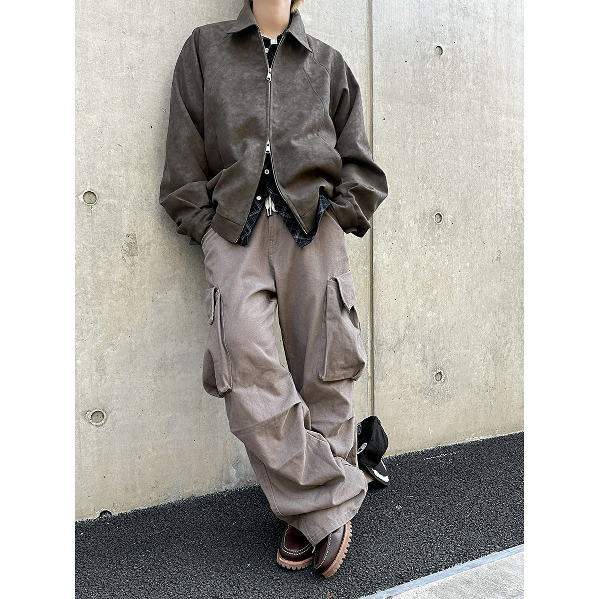 Front view of a model wearing loose taupe cargo pants with large side flap pockets.