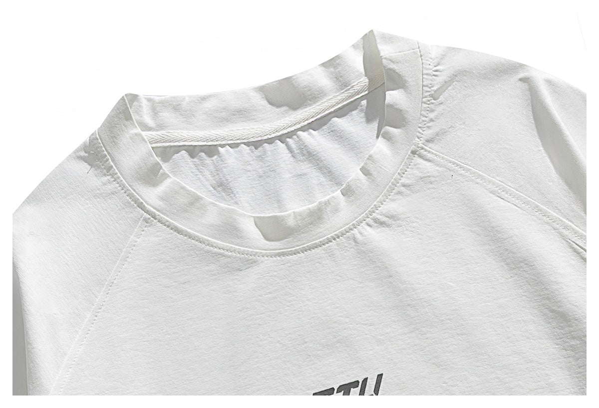 Close-up of a white crew-neck shirt with raglan seams and a small portion of dark chest lettering visible.