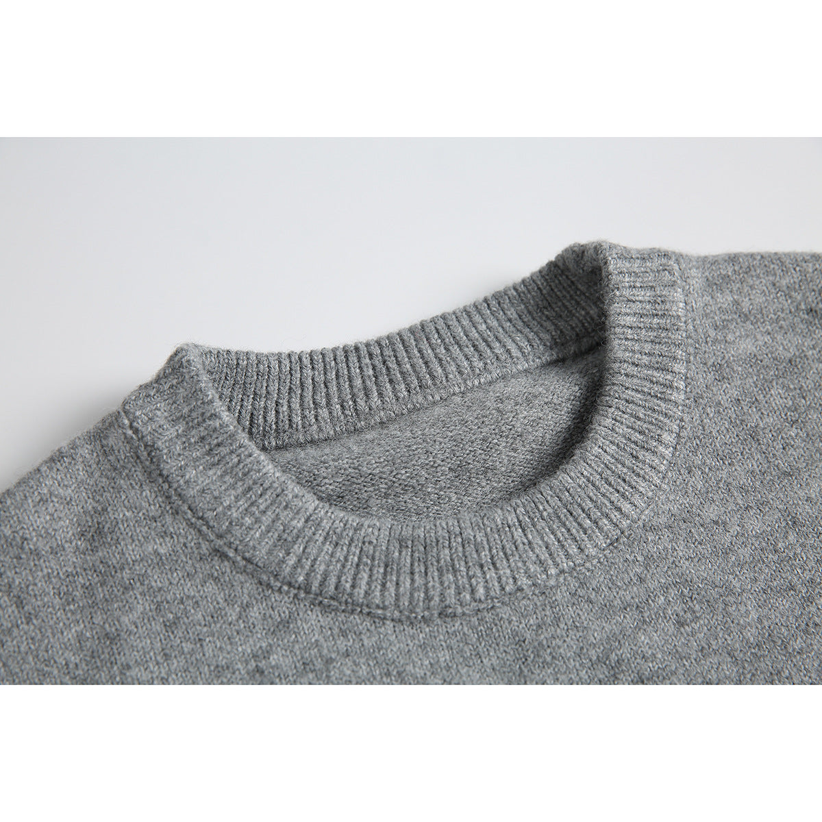 Close-up of a gray sweater's ribbed crew neckline and knit texture.