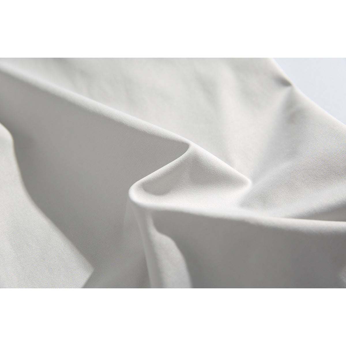 Close-up of light gray trouser fabric draped into soft folds.