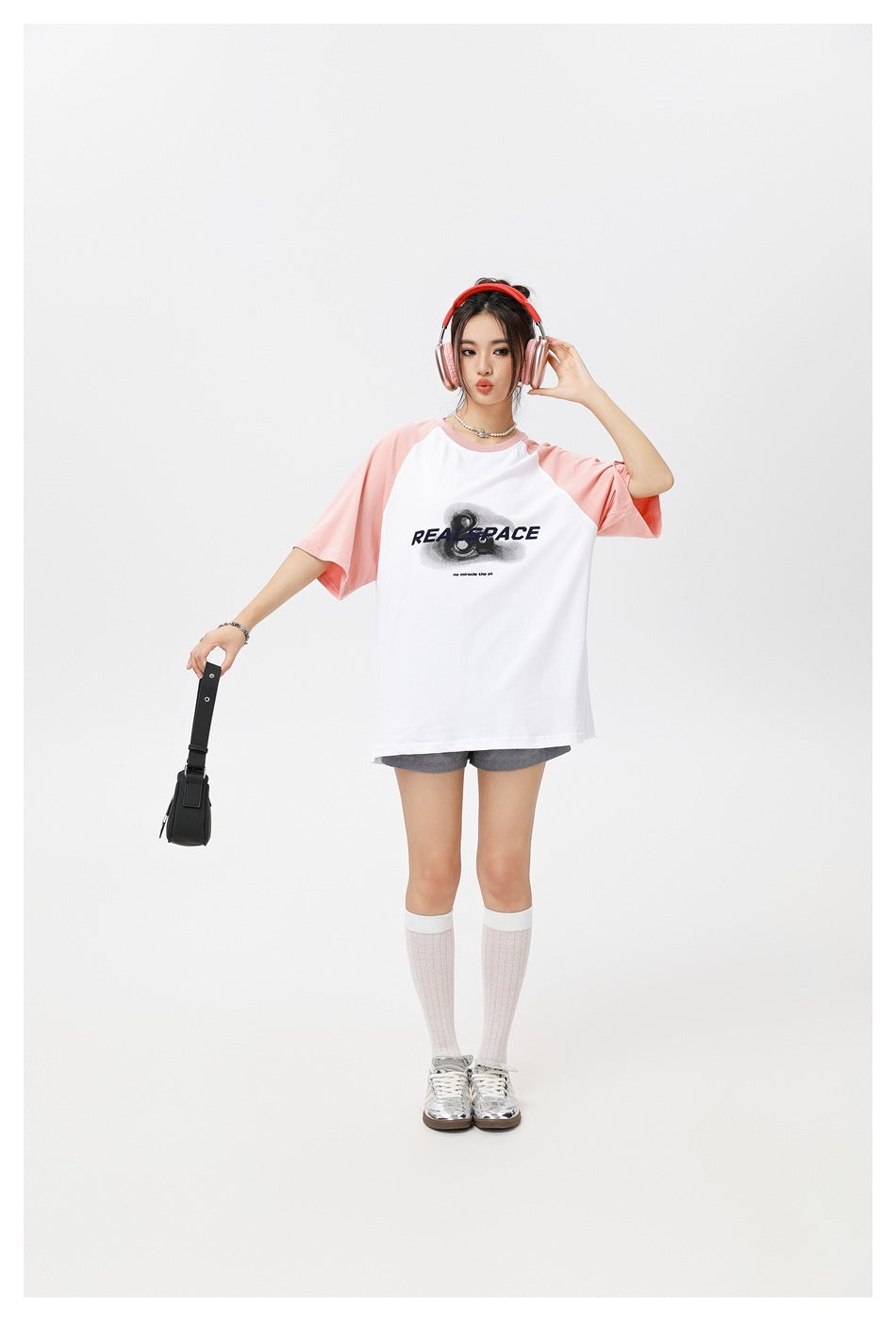 Full-length model wearing an oversized white T-shirt with pink raglan sleeves and a large black chest graphic.