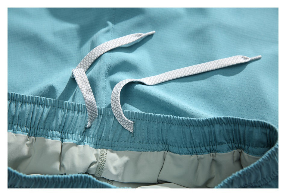 Close-up of turquoise shorts with a gathered elastic waistband and white drawstrings.