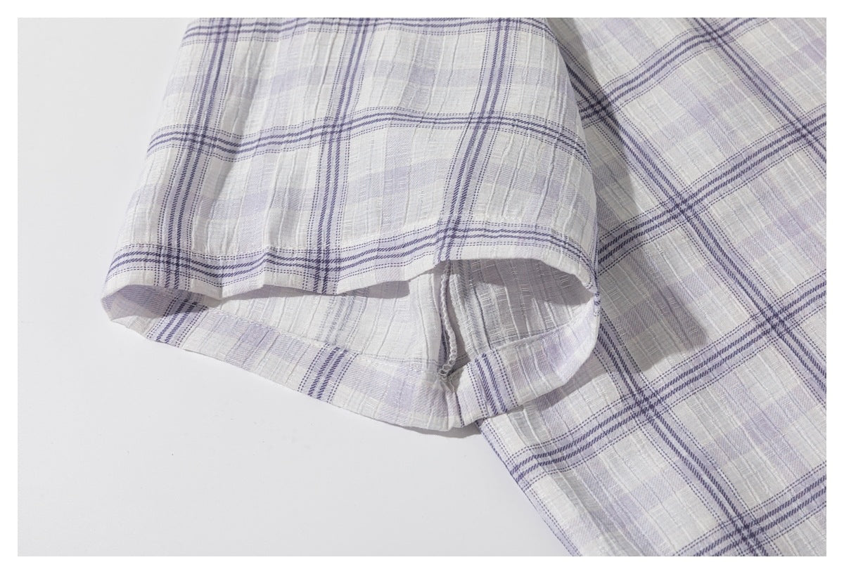 Close-up of a short sleeve and stitched hem on a light gray-lavender plaid shirt.
