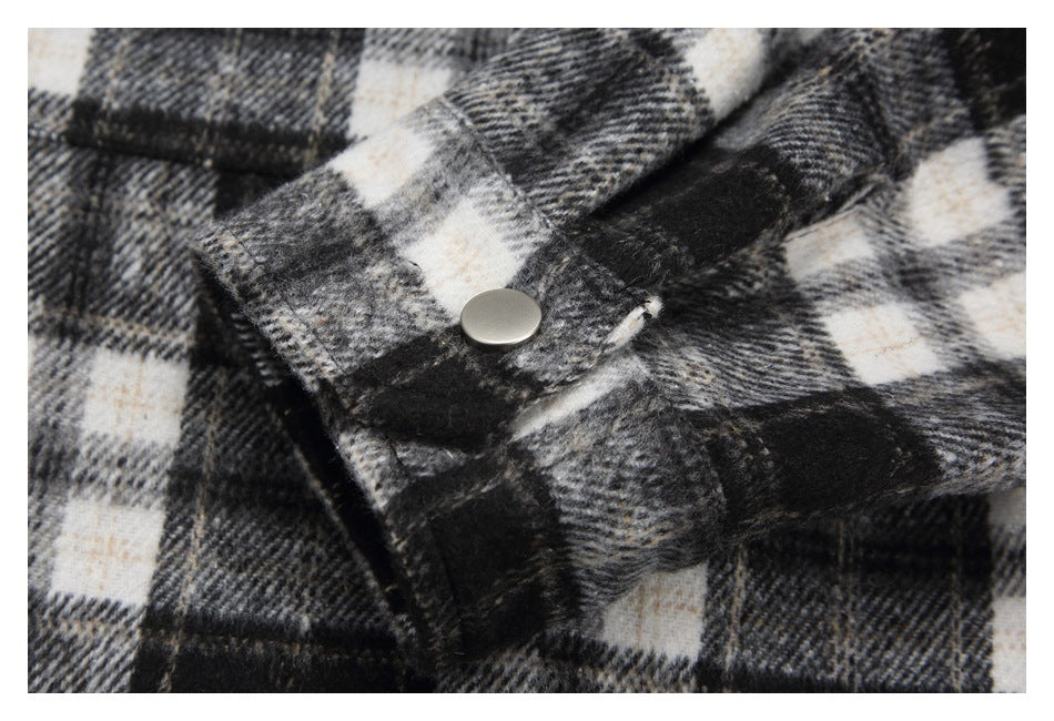 Close-up of a silver snap fastener on a black, gray, and cream plaid garment flap.