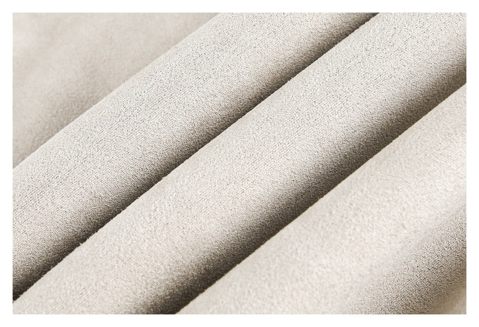 Close-up of light beige fabric folded into soft ridges, showing its fine surface texture.