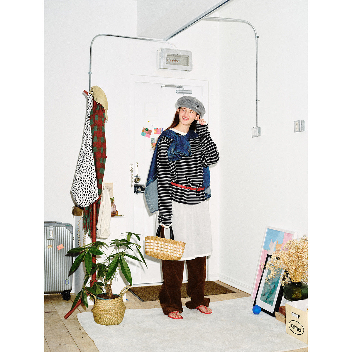 Model in a black-and-white striped long-sleeve top with a white apron-style layer, red belt and denim draped over her