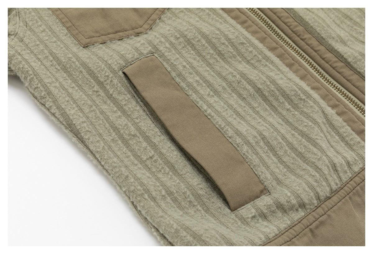 Close-up of a narrow taupe fabric tab on the striped body panel beside the jacket's front zipper.