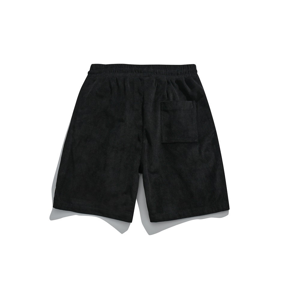 Back view of black corduroy shorts with an elastic waistband and a patch pocket.