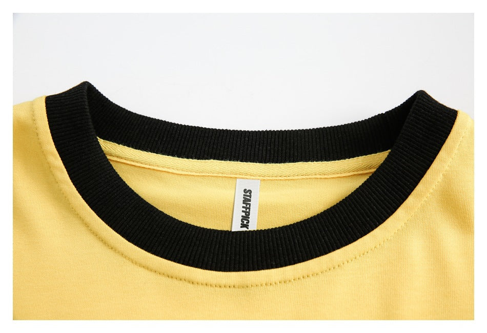 Close-up of the yellow shirt's black ribbed crew neck and inner neck label.