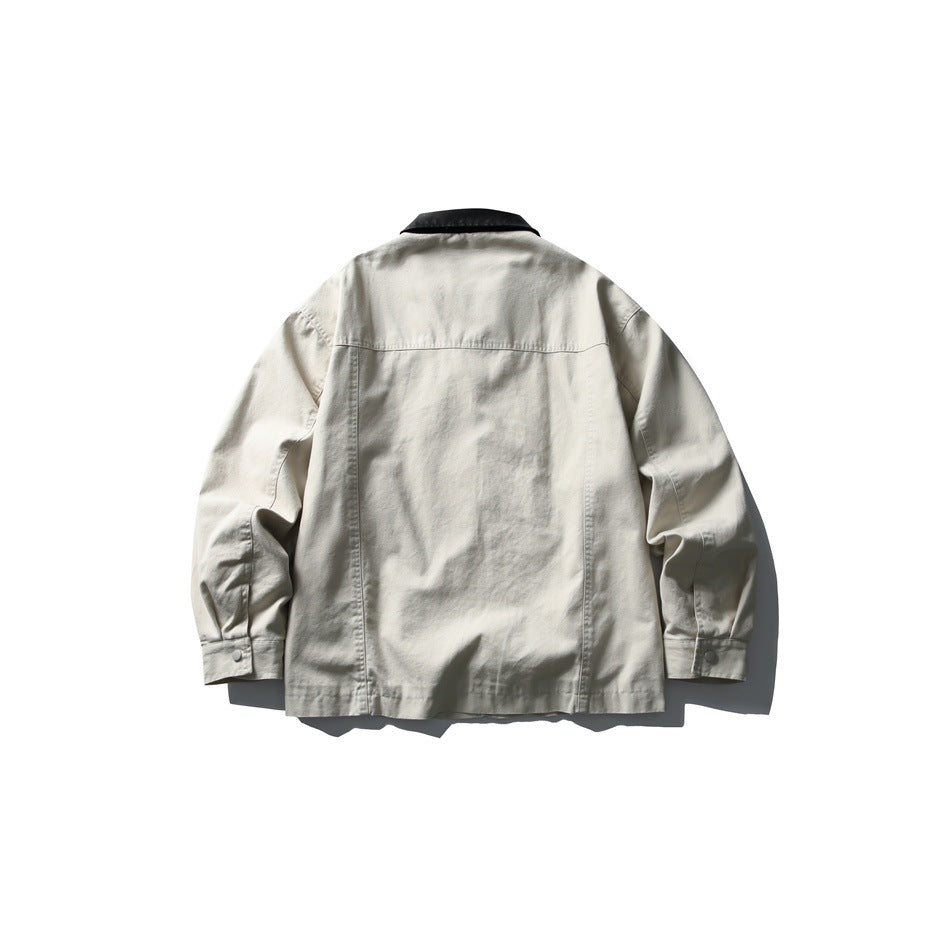 Back view of beige jacket with black collar, back yoke seam and snap-button cuffs, flat lay