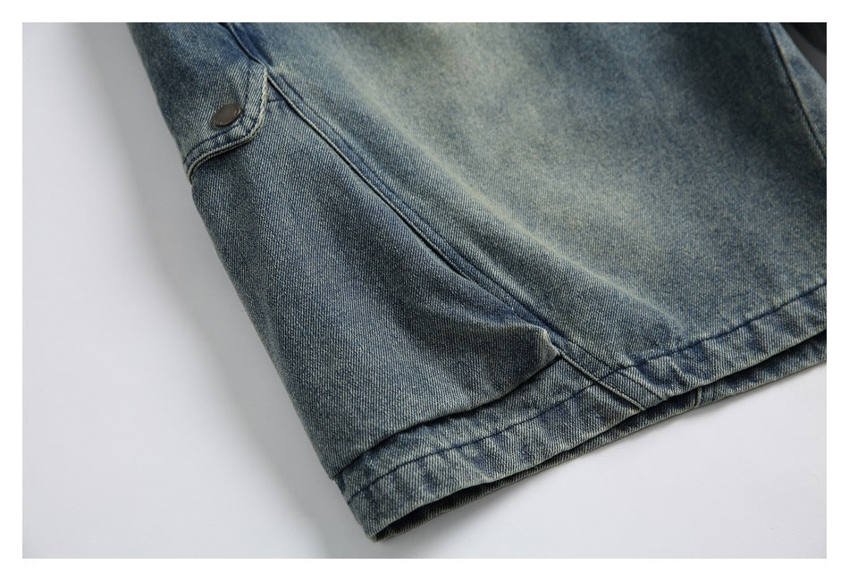 Close-up of blue denim garment hem with a small buttoned tab and visible stitching.