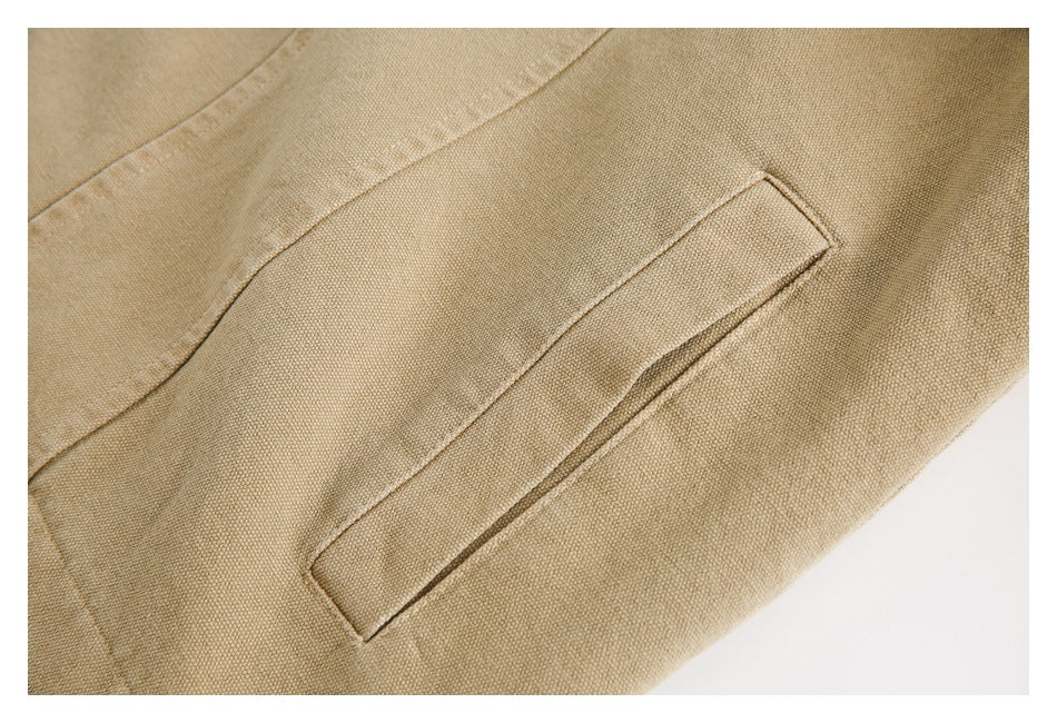 Close-up of a slanted welt pocket and stitched seams on the tan jacket.