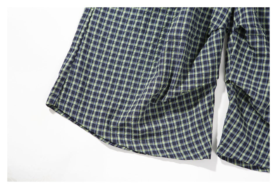 Close-up of the plaid shorts' legs and stitched hems.