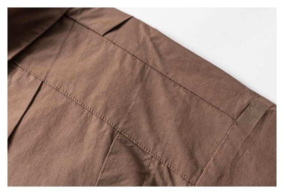 Close-up of brown garment fabric showing a long stitched seam and folded panel edges.