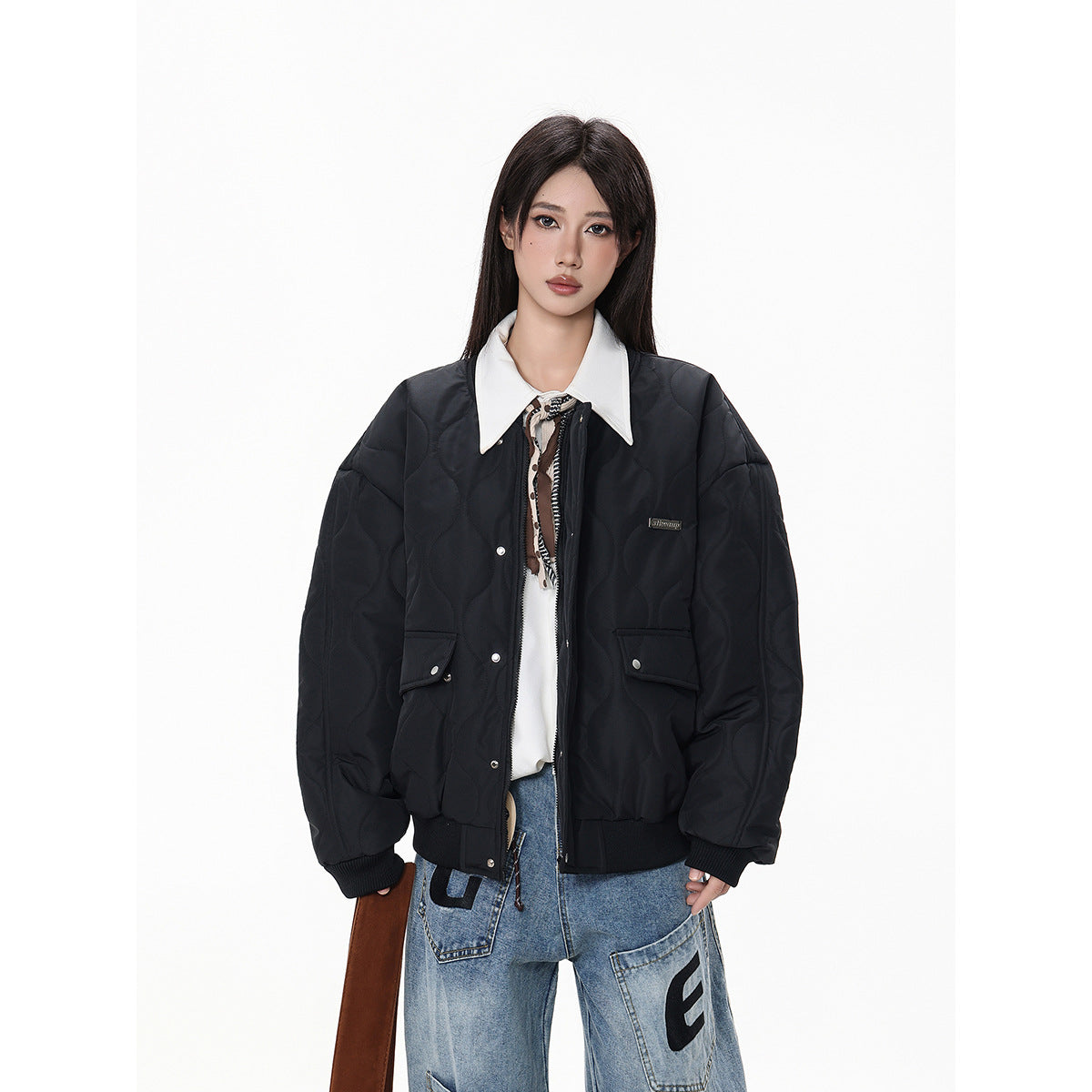 Front view of a model wearing a black quilted bomber jacket with snap-front closure, flap pockets and ribbed trim.
