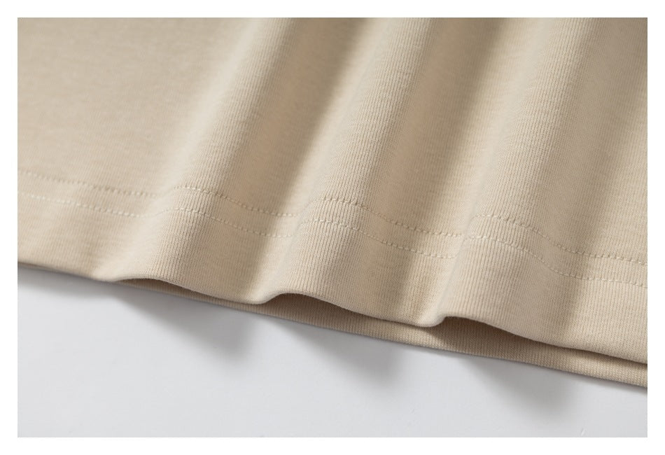 Close-up of the beige garment's folded hem and parallel stitching.