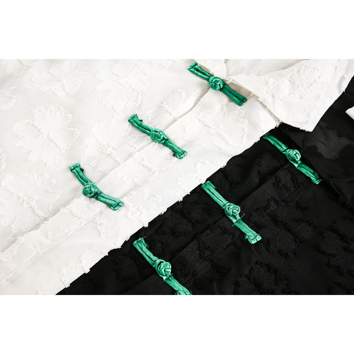 Close-up of white and black floral-textured fabric with bright green knotted frog closures.