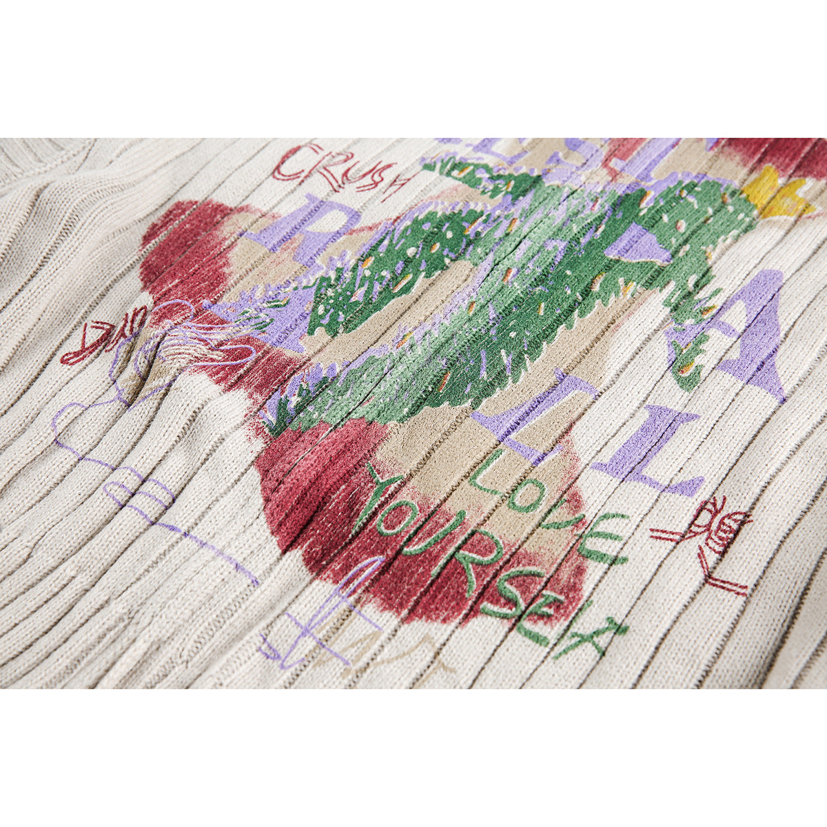 Close-up of colorful red, green, and purple graphic lettering printed on ivory ribbed knit.