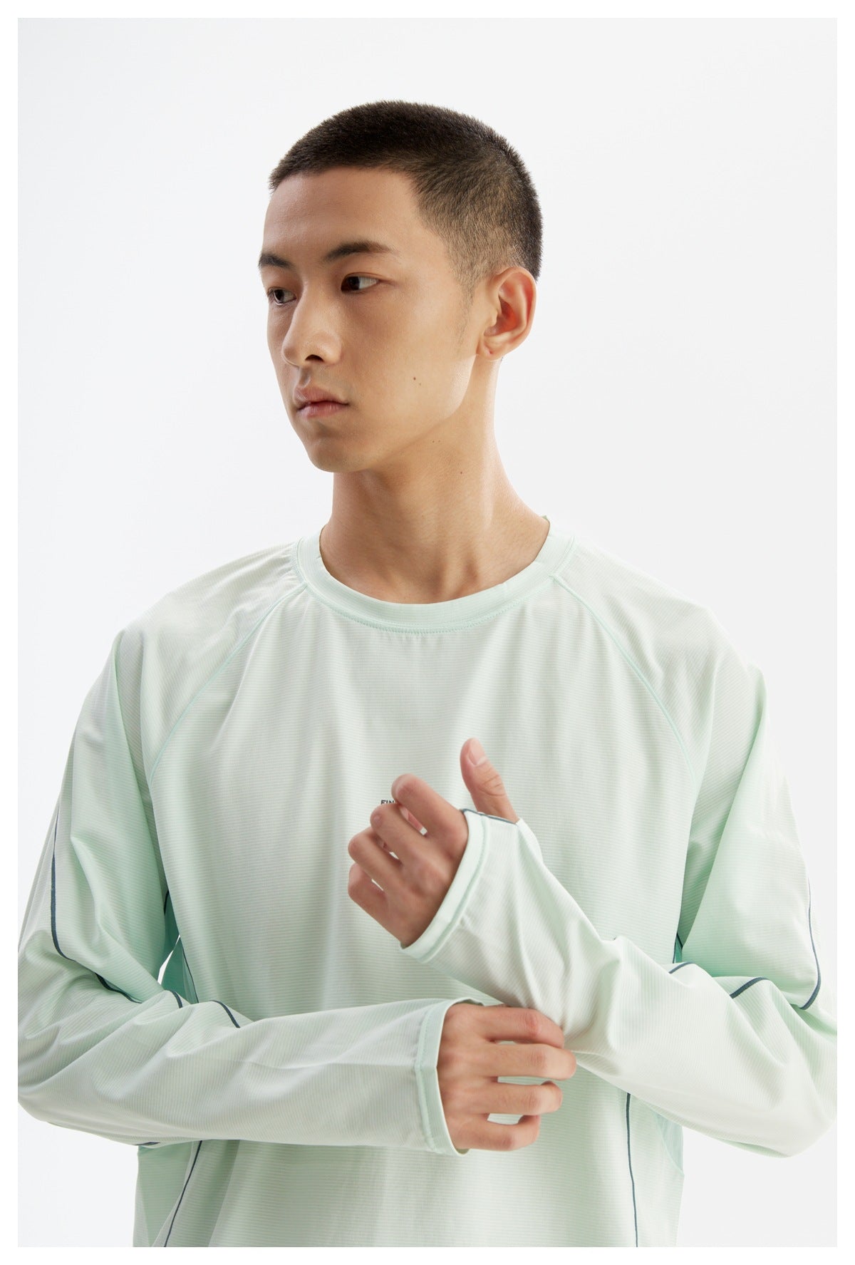Close front view of a man wearing a pale mint shirt, highlighting its crew neck, raglan seams, and long cuffs.