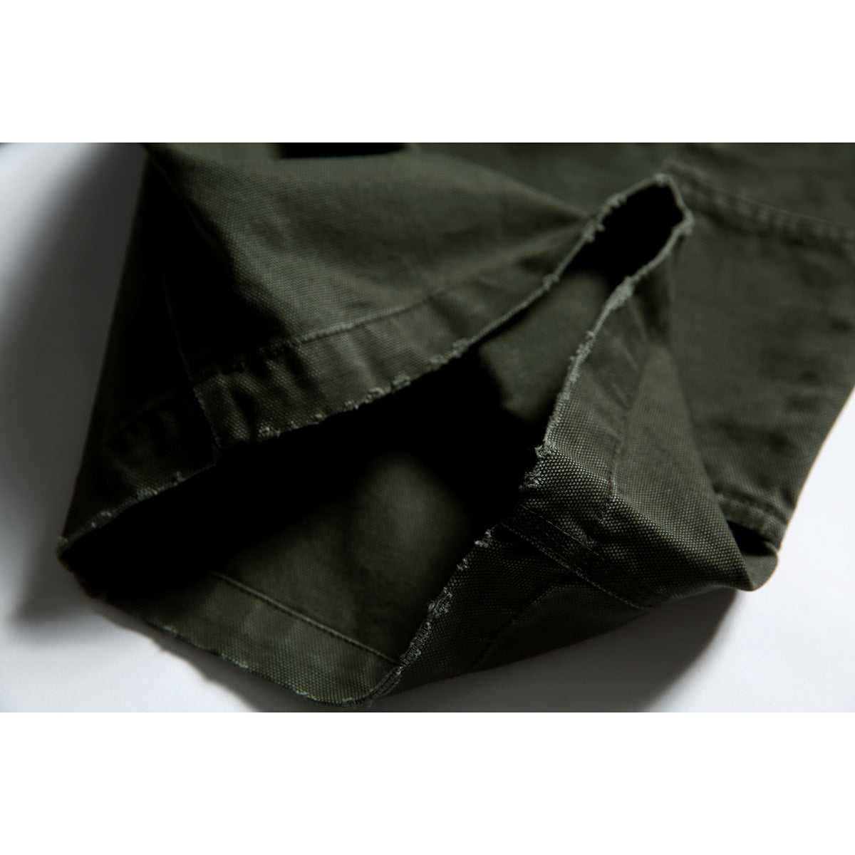 Close-up of the olive shorts' folded hem and interior stitching.