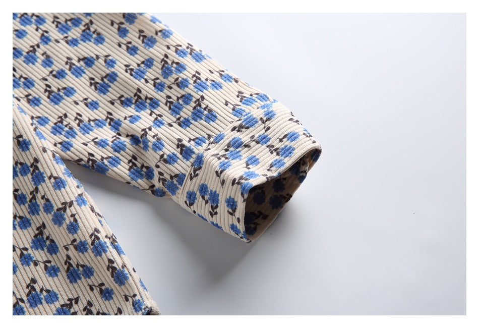 Close-up of a long sleeve and cuff on the beige shirt with blue and dark floral print.