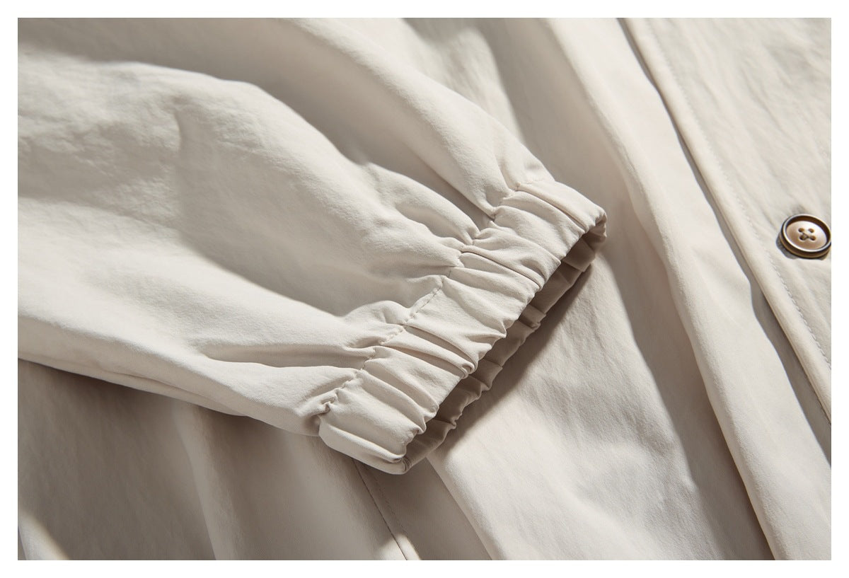 Close-up of an off-white sleeve with a gathered elastic cuff beside the garment's button placket.