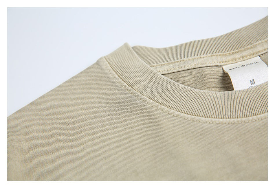 Close-up of the sand-beige T-shirt's ribbed collar, stitching, and inner size label.