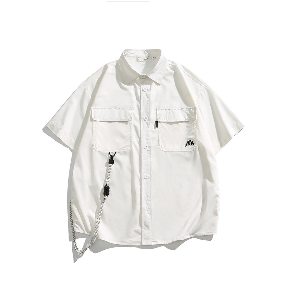 White short-sleeve button-up shirt with two flap chest pockets, black mountain logo and a hanging cord, flat lay front