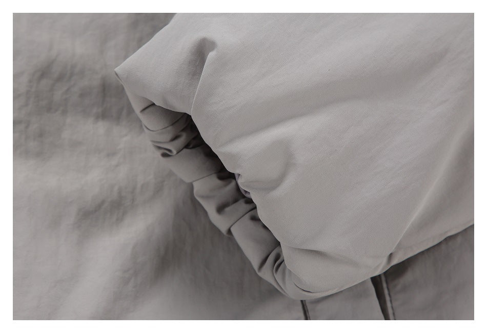 Close-up of gathered stitching and folded light gray fabric on a garment.
