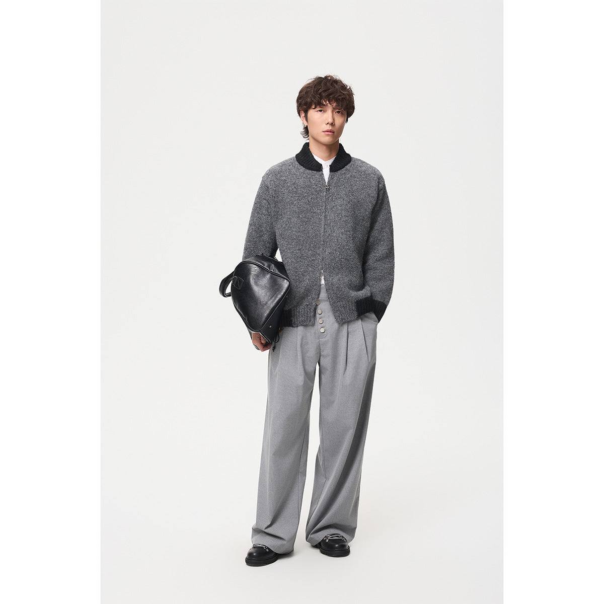 Full-length model wearing a dark gray knit jacket with black trim, gray trousers and black shoes.