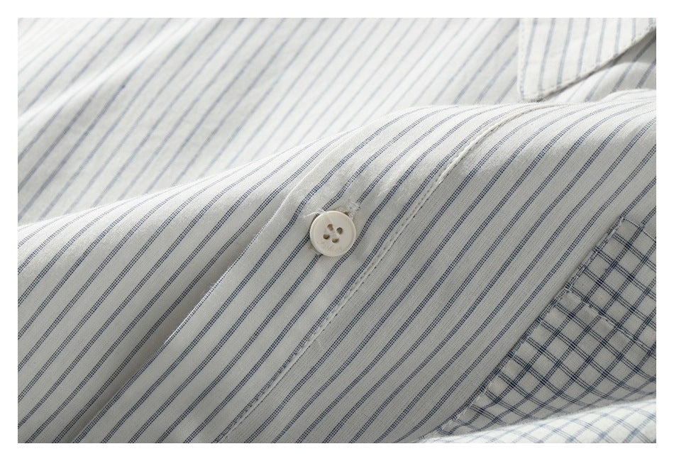 Close-up of a white shirt with fine blue-gray stripes and a cream button.