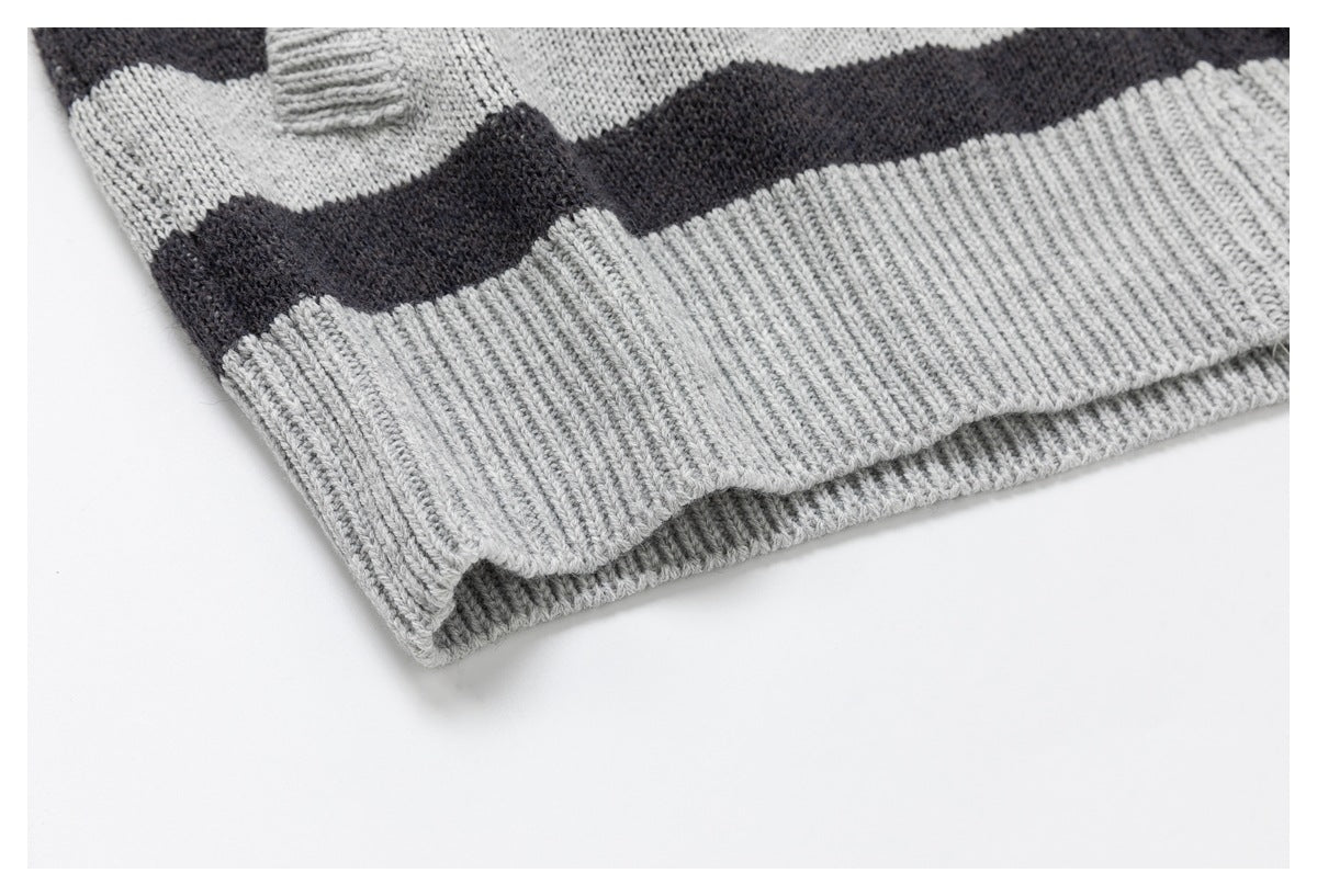 Close-up of the wide ribbed hem on a gray-and-charcoal striped knit garment.