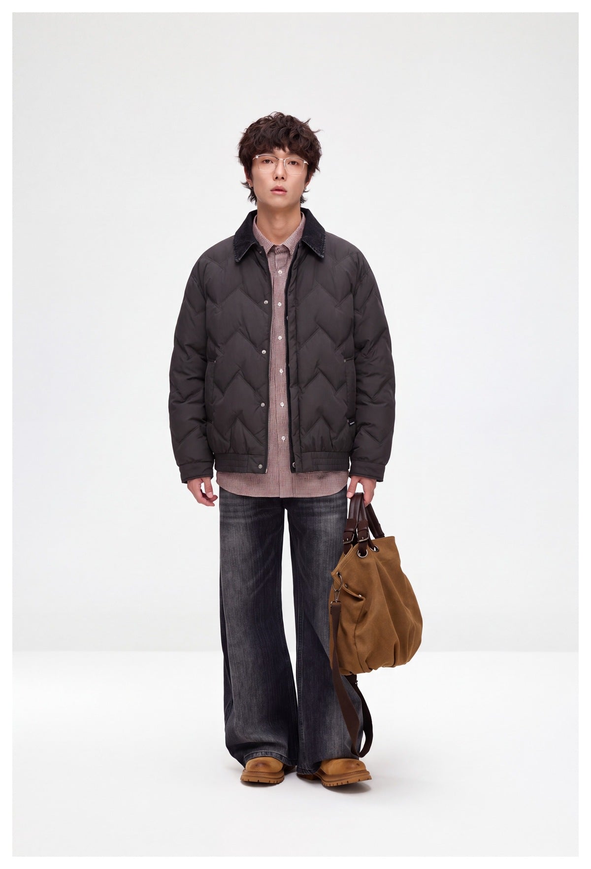 Model wearing a dark charcoal chevron-quilted jacket with a dark pointed collar, gingham shirt, and wide-leg jeans.