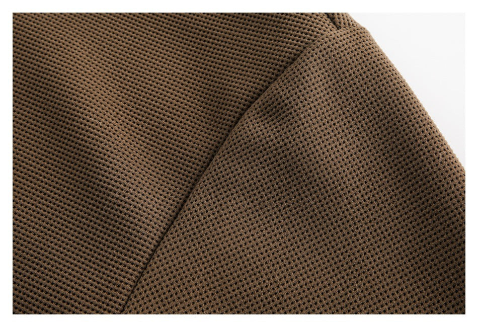 Close-up of brown waffle-knit fabric and a curved stitched seam.