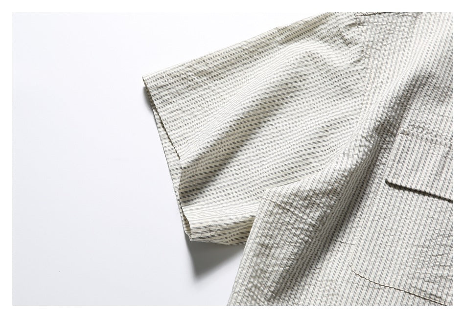 Close-up of the striped shirt's short sleeve and chest pocket on a white background.