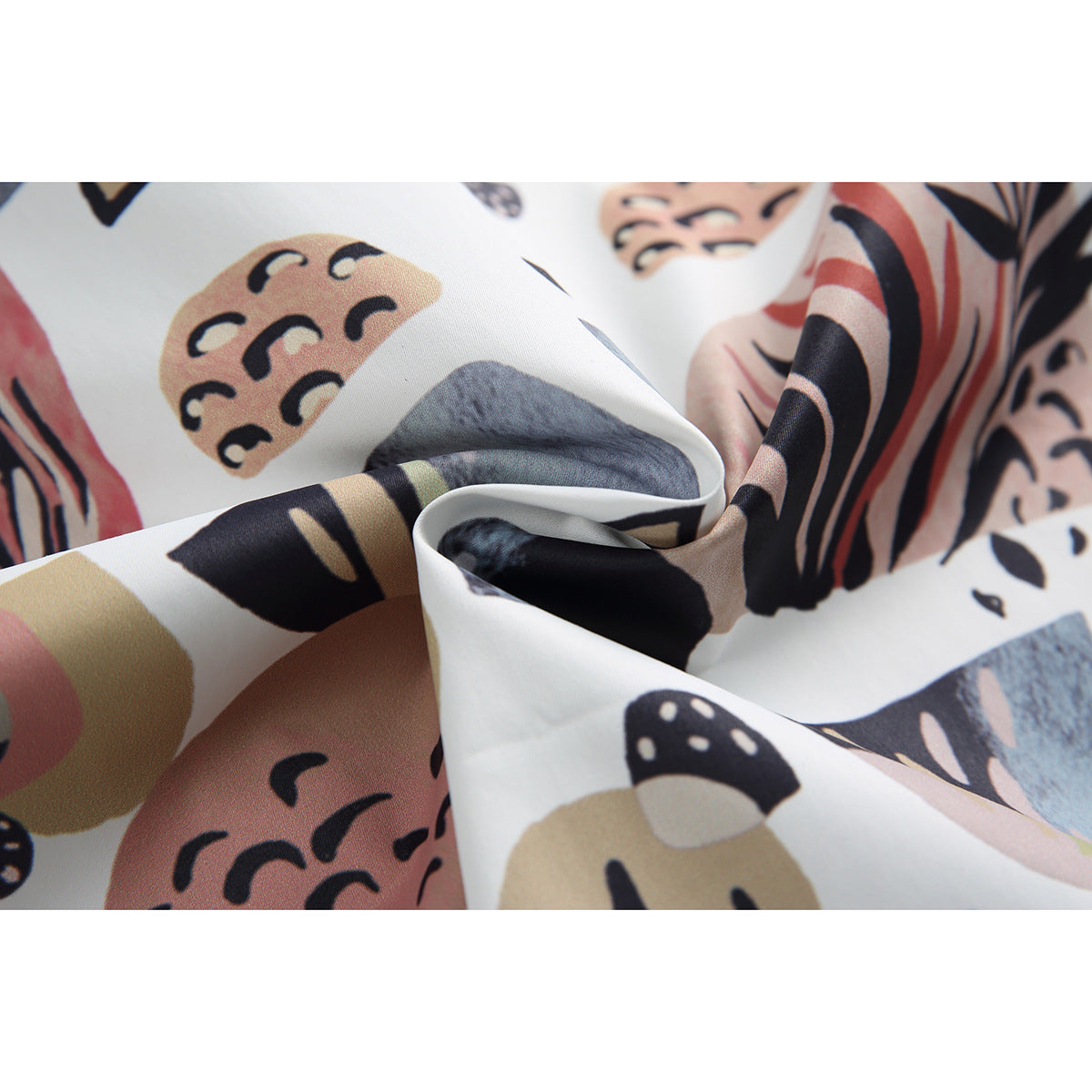 Close-up of the shirt's abstract botanical print in black, blush, tan, and blue on white fabric.