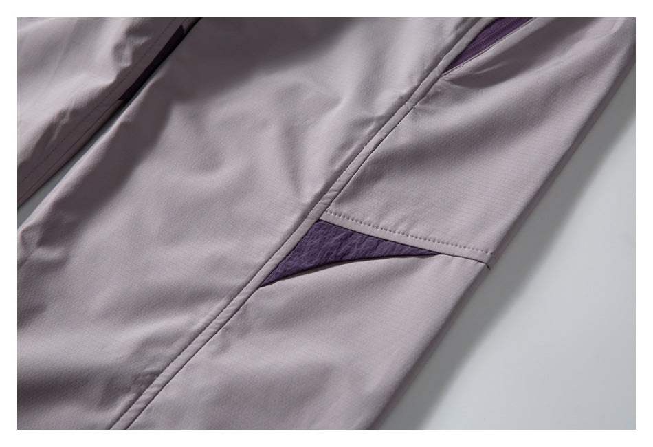 Close-up of mauve-gray pants with a small triangular purple fabric insert along a seam.