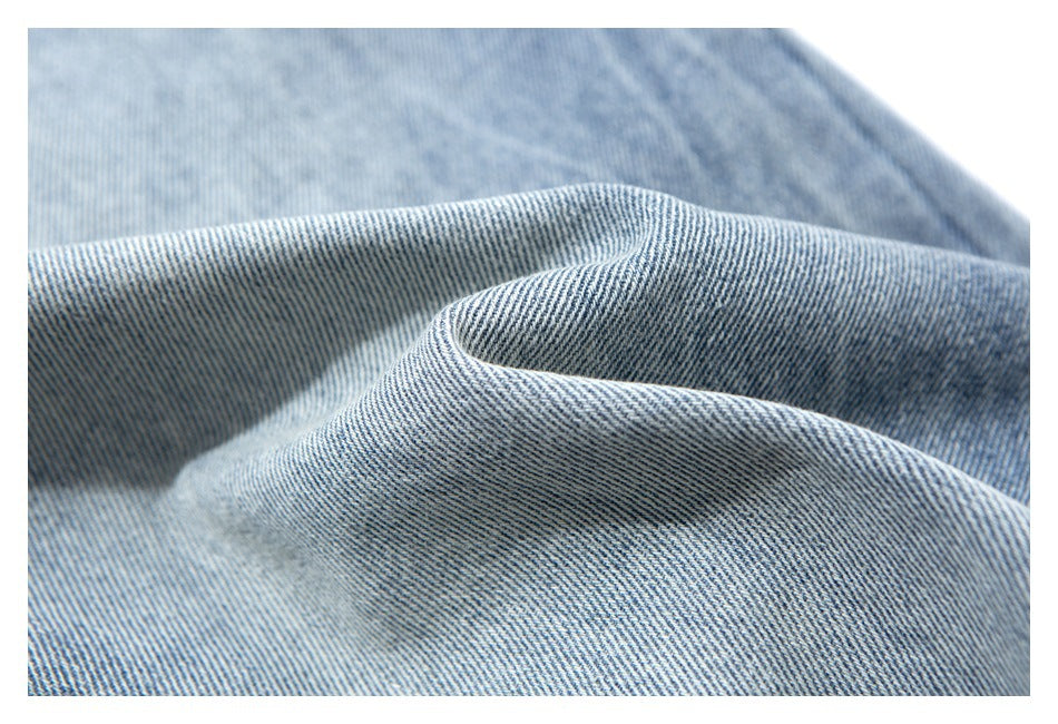 Macro view of the blue-and-white diagonal weave and folds of the denim fabric.