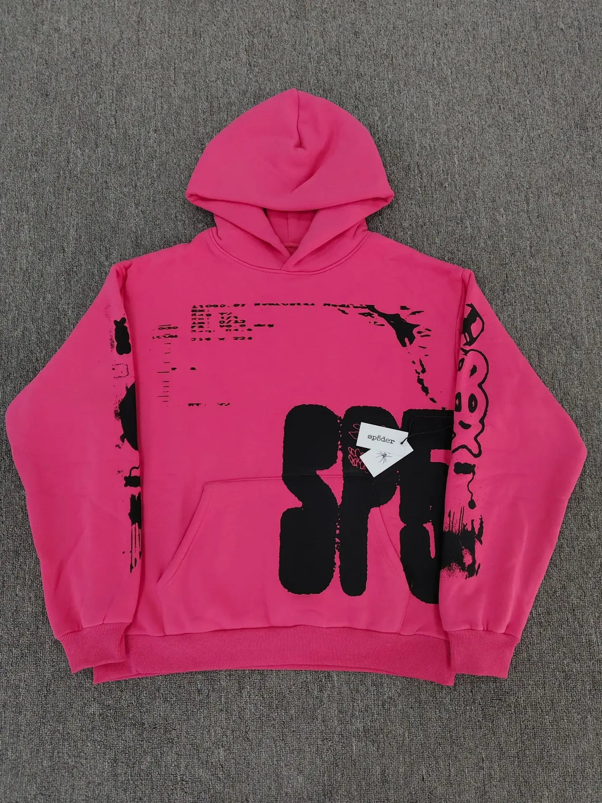 Hot pink Sp5der hoodie with bold black oversized graphic print on chest and sleeves laid flat on grey surface