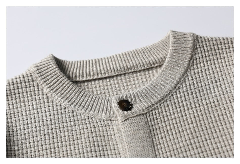 Close-up of a light gray textured knit cardigan collar and placket with a dark button.