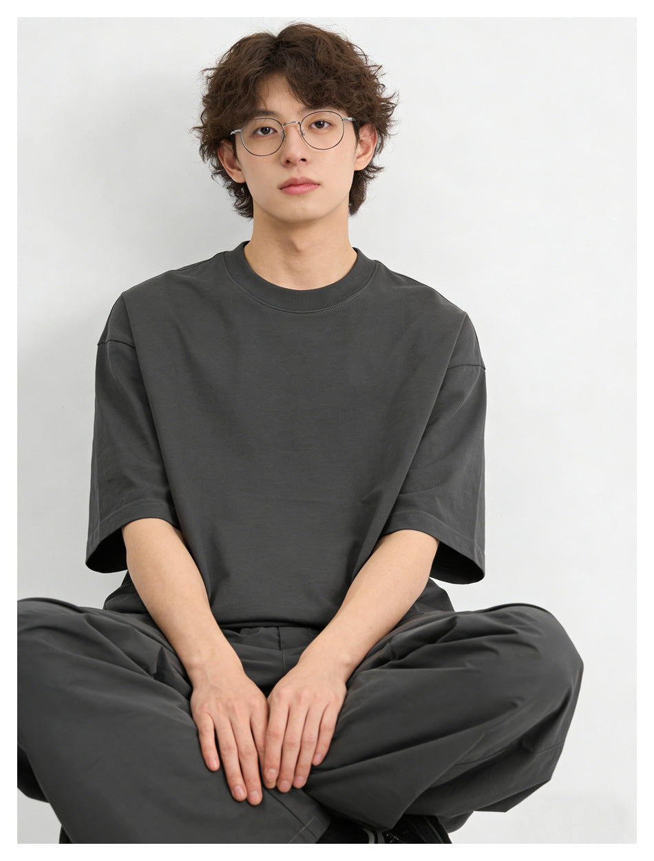 Model seated wearing an oversized charcoal short-sleeve crew-neck T-shirt and matching wide-leg pants.