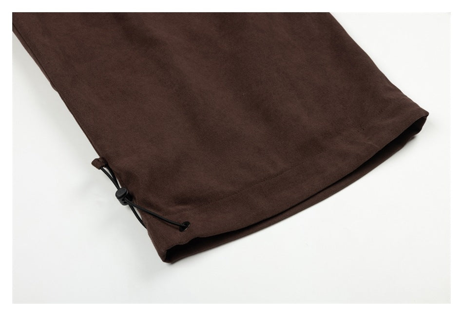 Close-up of a dark brown pant leg hem with a black adjustable cord and toggle.