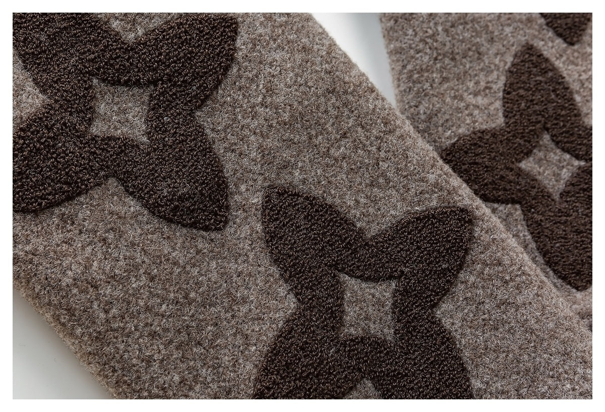 Close-up of dark brown bow-shaped motifs on beige textured knit fabric.