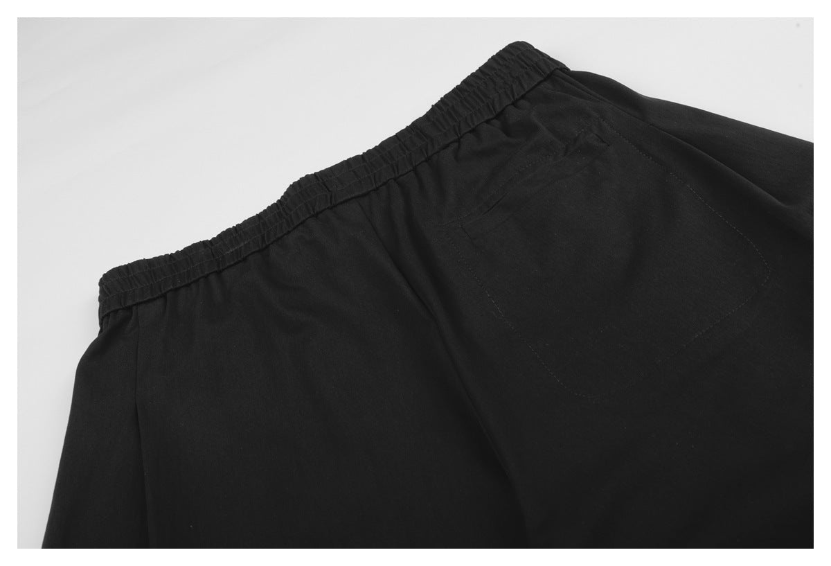 Close-up of black trousers showing the elastic waistband and a rear pocket.