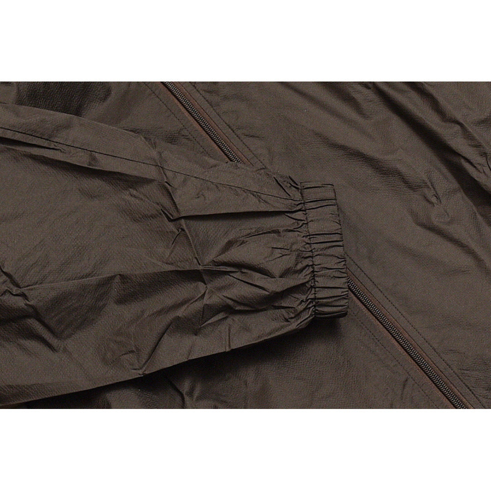 Close-up of a dark jacket sleeve with a gathered elastic cuff beside the front zipper.