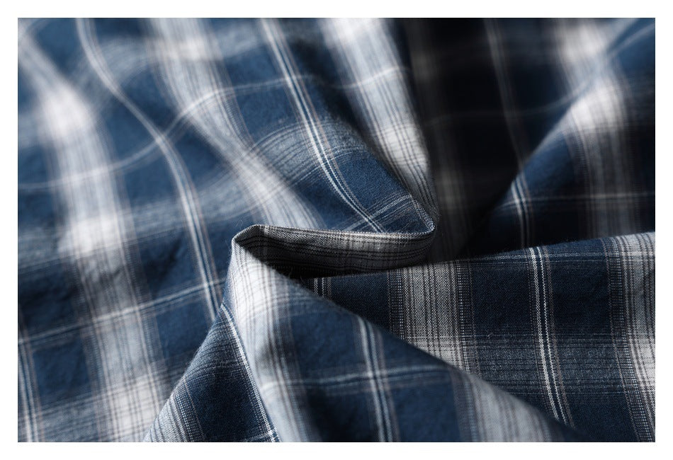 Close-up of navy, gray, and white plaid fabric draped in soft folds.